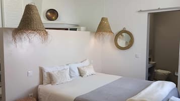 Un dormitorio con una cama, dos lámparas colgantes, un espejo y un armario.