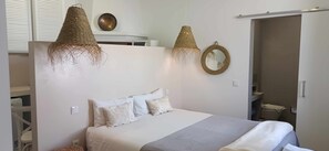 Ein Schlafzimmer mit einem Bett, zwei Pendelleuchten, einem Spiegel und einem Kleiderschrank.