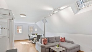 A modern living room with a grey sofa, a coffee table, and a dining area in the background. - Lovely apartment for 5 guests with WIFI and TV (Endingen)