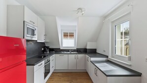 A modern kitchen with white cabinets, a red refrigerator, and a window providing natural light. - Lovely apartment for 5 guests with WIFI and TV (Endingen)
