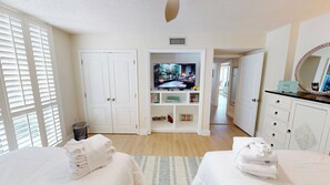 Une chambre d’hôtel avec deux lits, une télévision, une armoire et un couloir menant à une autre pièce.
