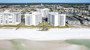 Ein Hochhaus-Hotel mit Innenhof, nahe einem Strand mit Blick auf den Ozean und einen Hafen.