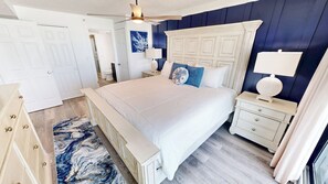 Ein Schlafzimmer mit einem Bett, Nachttischen, einem Deckenventilator und einem Teppich mit Marmor-Muster.