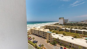 Ein Hotel direkt am Strand mit mehreren Stockwerken, einem Parkplatz und Blick auf das Meer und den Strand.