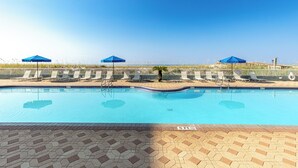 A swimming pool with lounge chairs and umbrellas, surrounded by a fence and a clear sky. - Stunning GulfView Islander Beach Resort 405 (Fort Walton Beach)