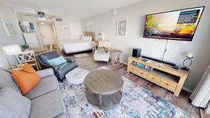 A modern living room with a sofa, armchair, ottoman, round coffee table, TV, and a wooden entertainment unit. - Stunning GulfView Islander Beach Resort 405 (Fort Walton Beach)