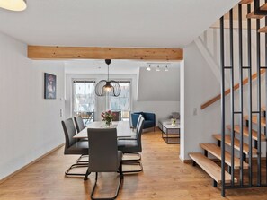 Ein modernes Interieur mit Essbereich, einer Treppe und Blick auf einen Balkon.