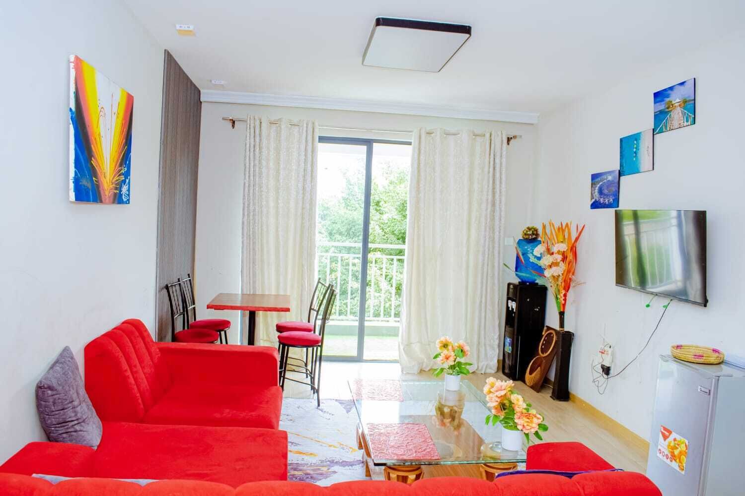 Una sala de estar con un sofá rojo, una mesa de centro de vidrio y un comedor con mesa y sillas.