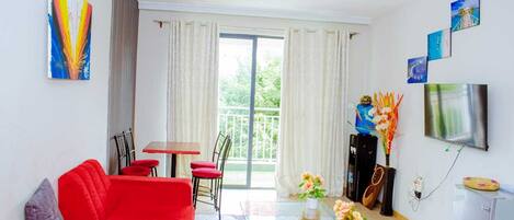 Una sala de estar con un sofá rojo, una mesa de centro de vidrio y un comedor con mesa y sillas.