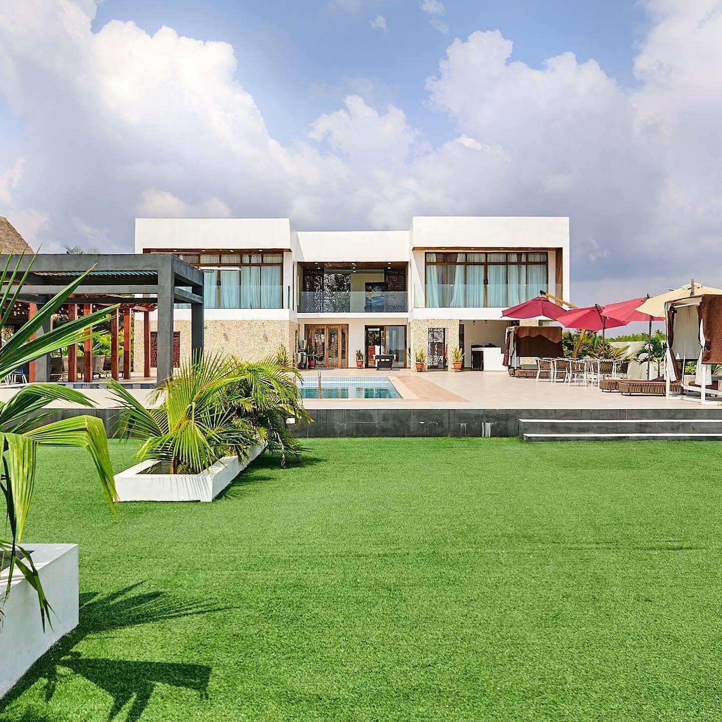 A modern hotel with a swimming pool, outdoor seating, and a well-maintained lawn.