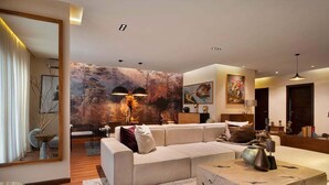 A modern living room with a sectional sofa, a coffee table, and a large abstract painting on the wall.