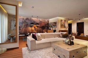A modern living room with a sectional sofa, a coffee table, and a large abstract painting on the wall.