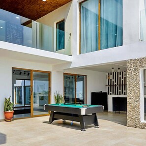 A modern multi-level house with a pool table, glass doors, and a stone wall. - Havara Resorts & Residences (Lagos)
