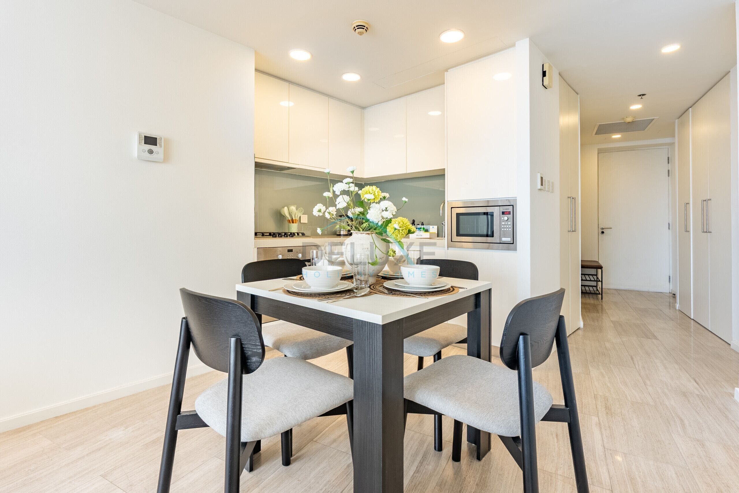 A modern kitchen with white cabinets, a microwave, and a dining area with a table set for two.