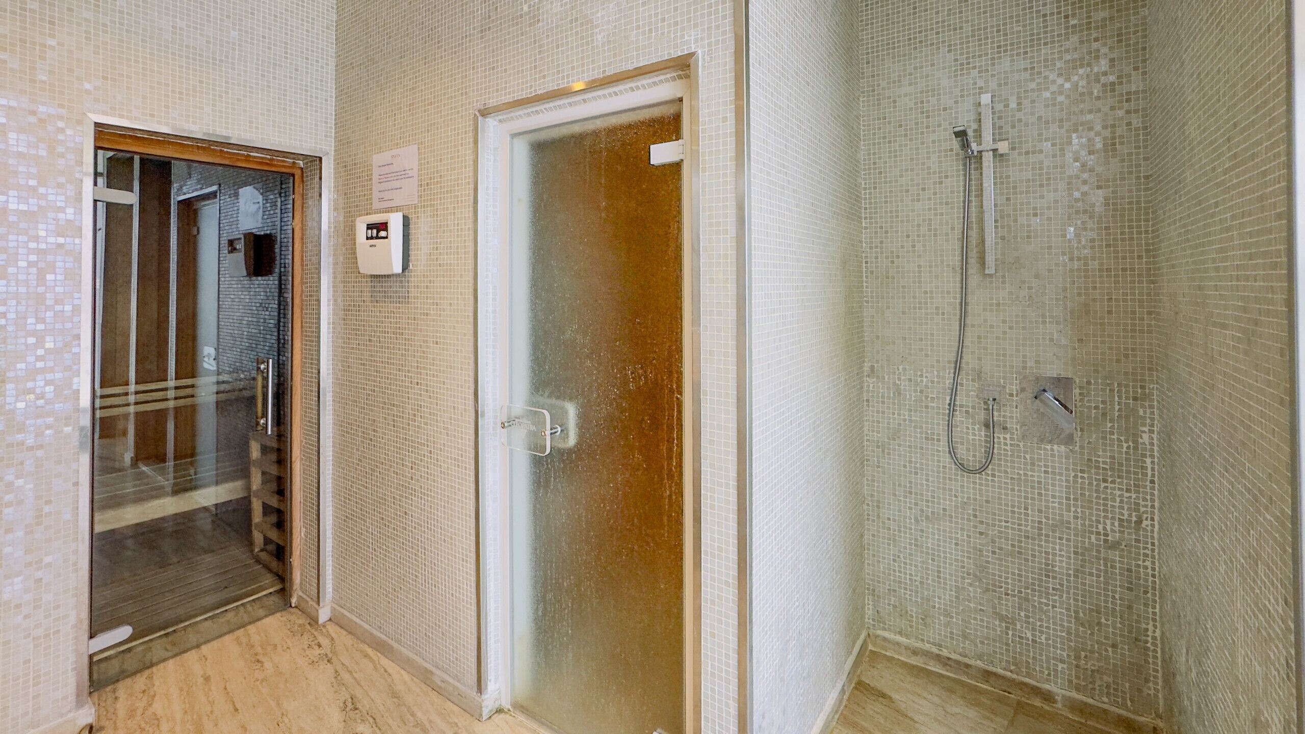A bathroom with a shower, a glass door, and a tiled wall.