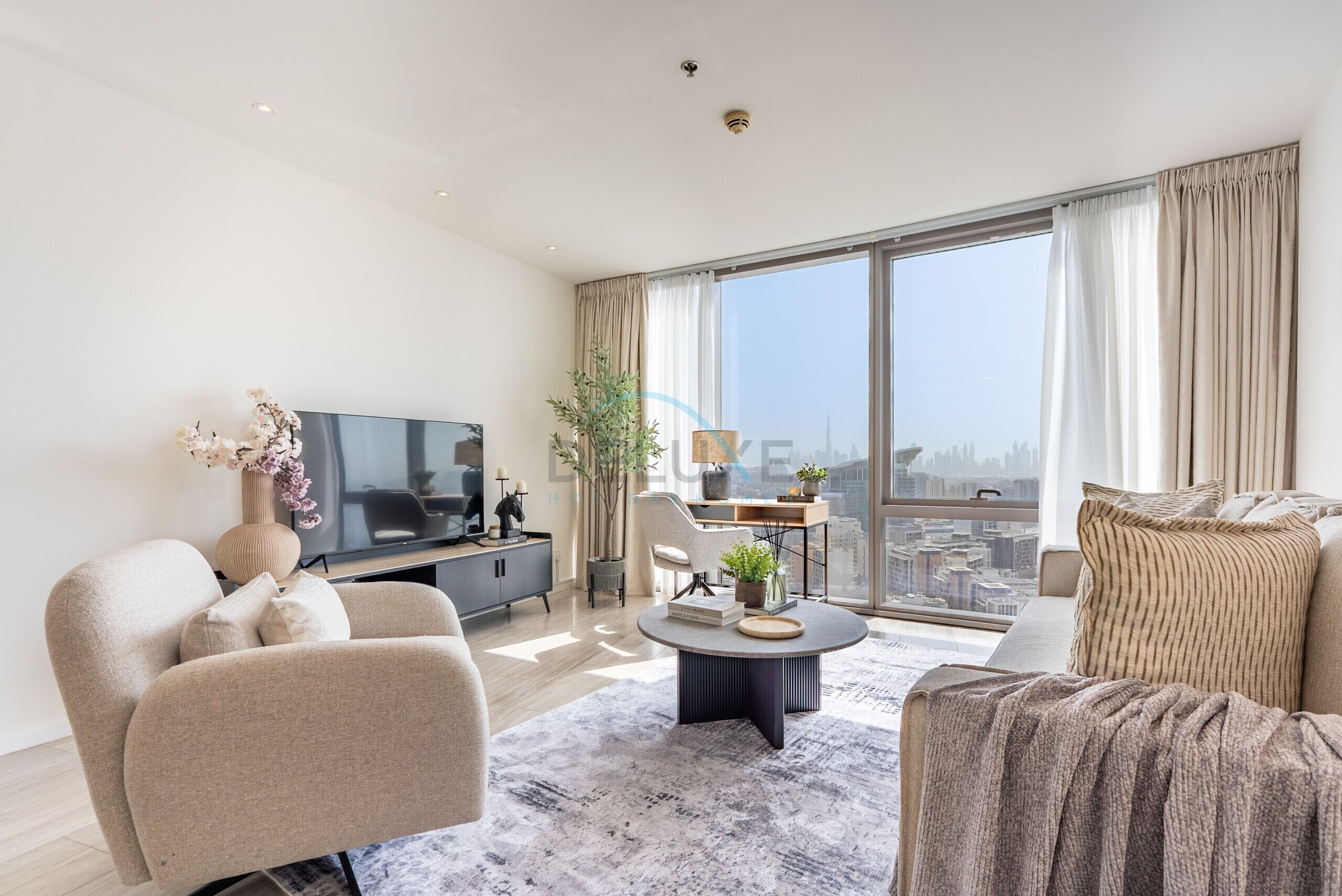 Een moderne woonkamer met een flatscreen televisie, een bank, een salontafel en een groot raam met uitzicht op de stad.