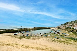 Eine Küstenbucht mit vor Anker liegenden Booten, einem Sandstrand und einem Steg.