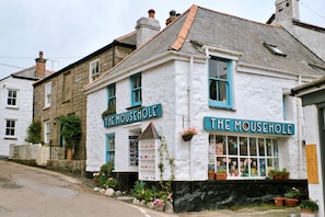 Ein weißes Gebäude mit blauer Fassade und einem Schild, auf dem 'The Mousehole' steht.