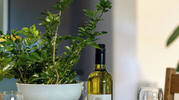Uma mesa de jantar com uma tigela branca, uma garrafa de vinho e um vaso de planta.
