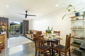 Ein modernes Wohnzimmer mit Essbereich, Deckenventilator und Blick auf eine Terrasse.