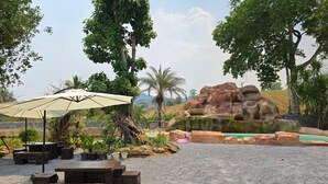 Eine Terrasse mit Gartenmöbeln, einer Felsformation und einem kleinen Wasserspiel.