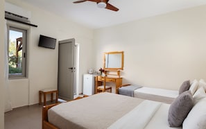 Un dormitorio con cama, escritorio, silla, televisor y ventilador de techo.