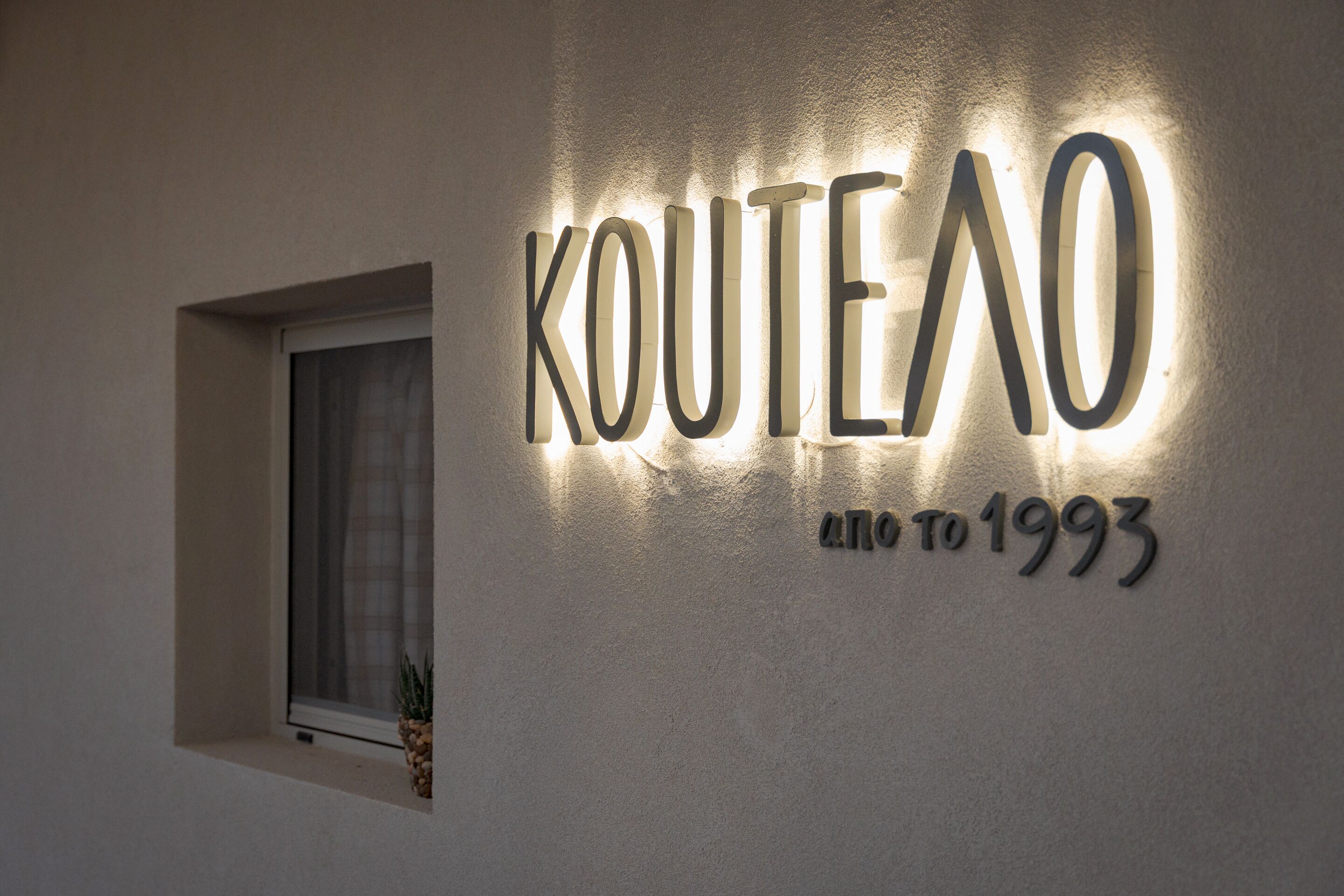 A wall with the text 'KOUTEO' and 'since 1993' illuminated in lights.