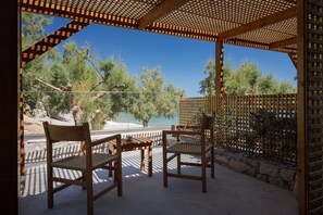 A wooden pergola with two chairs and a table, overlooking a clear blue sky and a body of water. - Koutelo by The Sea (Sfakia)
