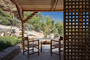 A covered outdoor seating area with two chairs and a table, surrounded by a wooden pergola and a lattice fence. - Koutelo by The Sea (Sfakia)