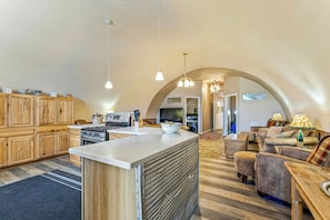 Una cocina amplia con armarios de madera, una isla central y una zona de comedor con sofá y mesa.