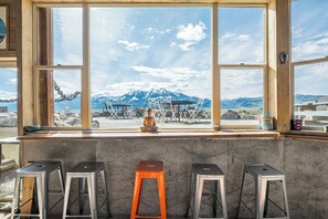Zona de bar con taburetes, una estatua de Buda y vistas a las montañas a través de amplias ventanas.
