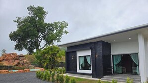 Een modern gebouw met een grote boom, een terras en uitzicht op een natuurlandschap.