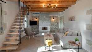 Ein modernes Interieur mit einer Holztreppe, einem Steinkamin und einer gemütlichen Sitzecke.