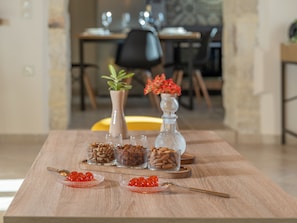A wooden table with glass containers of nuts and red caviar, a spoon, and a decorative vase with red flowers. - Luxury Villa Dimitra with Private Swimming pool (Kato Vathia)