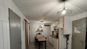 Eine kompakte Küche mit Esstisch und Stühlen, einer Mikrowelle und einer Kaffeemaschine.