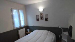 Ein Zimmer mit einem großen Bett, einem kleinen Tisch mit Lampe, einem Heizkörper und einer Wandleuchte.