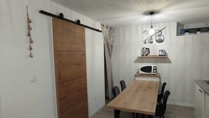 Eine kleine Küche mit Holztisch und Stühlen, einer Hängeleuchte und einer Schiebetür.