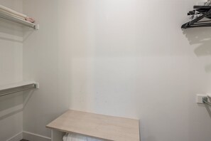 Ein Badezimmer mit weißer Wand, einem Holzregal und einem Handtuchhalter.