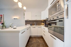 Eine moderne Küche mit weißen Schränken, einer Ziegelrückwand und Edelstahlgeräten.