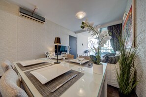 A dining area with a table set for two, a potted plant, and a sofa in the background. - St. Julian's Apartment 501 - Near Beach &Paceville (Saint Julian's)