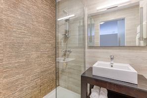 A modern bathroom with a glass shower enclosure, a white sink, and a wooden vanity. - St. Julian's Studio 202 - Near Beach & Paceville (Saint Julian's)