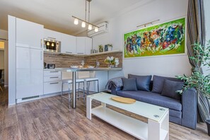 A modern kitchen with white cabinets, a stainless steel range, and a dining area with a white table and bar stools. - St. Julian's Studio 202 - Near Beach & Paceville (Saint Julian's)