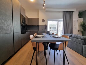Eine moderne Küche mit Essbereich, einem grauen Sofa und Blick ins Freie.