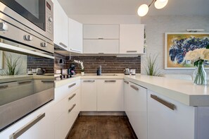 Eine moderne Küche mit weißen Schränken, einem Edelstahlherd und einem großen Gemälde an der Wand.