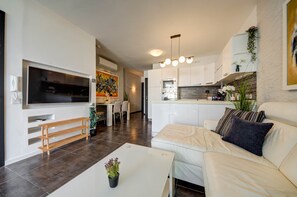 A modern living room with a flat-screen TV, a sofa, a coffee table, and a dining area with chairs. - St. Julian's Apartment 502 - Near Beach &Paceville (Saint Julian's)