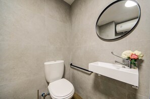 Ein Badezimmer mit Toilette, Waschbecken, Spiegel und Handtuchhalter.