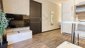 Une cuisine moderne dotée d’un téléviseur à écran plat, d’une porte en bois foncé et d’un plan de travail blanc.