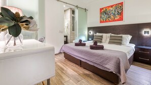 Une chambre à coucher moderne avec un lit, des tables de chevet, une commode, une cabine de douche en verre et un grand tableau abstrait.
