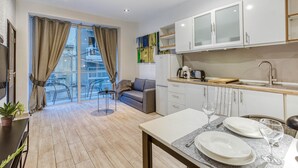 Um apartamento moderno com varanda, área de refeições e cozinha com armários brancos.
