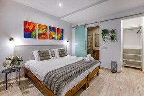 A modern bedroom with a wooden bed, white bedding, and colorful abstract art on the wall. - St. Julian's Studio 201 - Near Beach & Paceville (Saint Julian's)